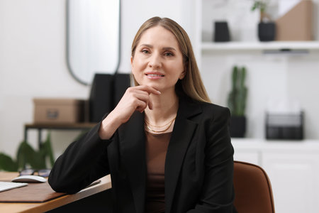 Portrait of smiling businesswoman in suit on chair in office