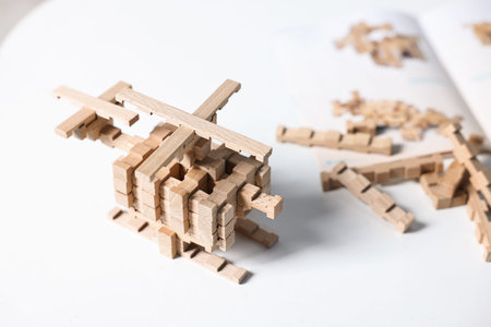 Helicopter figure made of wooden blocks on white table, closeup