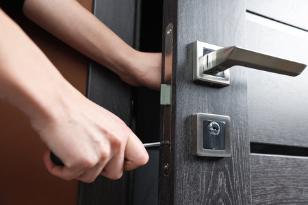 Woman opening wooden door with key indoors, closeup