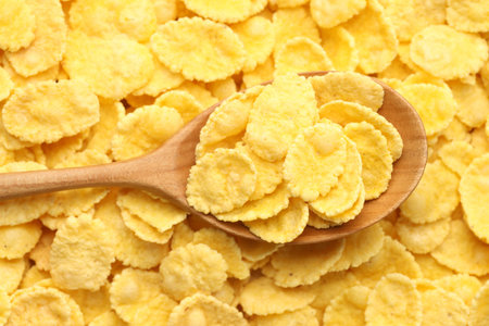 Tasty corn flakes and wooden spoon, top view
