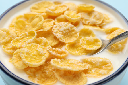 Tasty corn flakes with milk in bowl on table, closeup