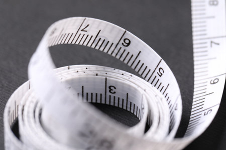 One measuring tape on black background, closeup