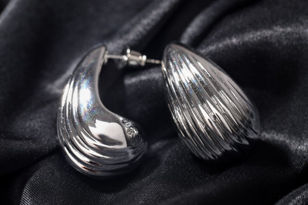 Beautiful silver earrings on black fabric, closeupの写真素材