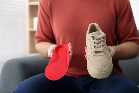 Man with orthopedic insole and shoe indoors, closeupの写真素材