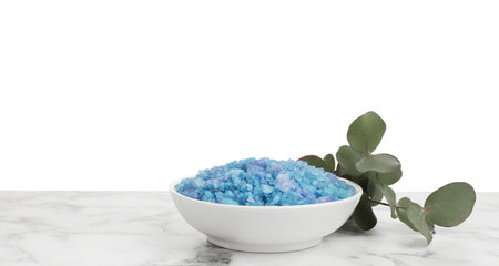 Blue sea salt in bowl and eucalyptus branch on marble table against white backgroundの写真素材