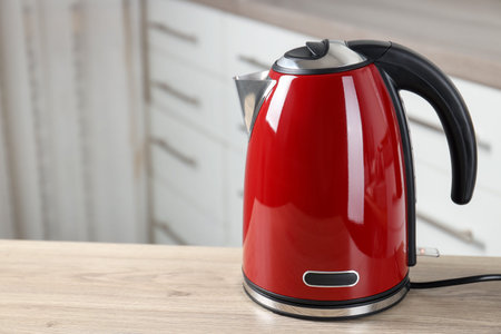Red electric kettle on wooden table indoors, closeup. Space for textの写真素材