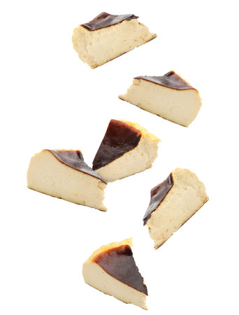 Delicious Basque cheesecake pieces falling on white background. Yummy dessert