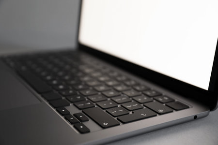 Modern laptop with blank screen on grey background, closeup
