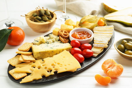 Charcuterie board with many different snacks on white wooden table, closeup