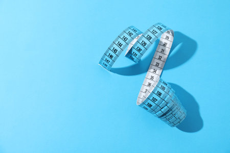 One measuring tape on light blue background, top view. Space for text