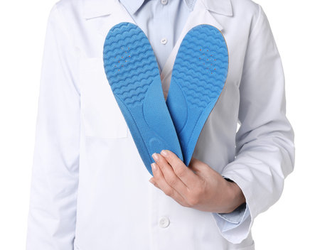 Orthopedist with foot insoles on white background, closeup