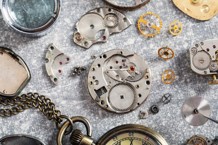 Mechanism of vintage wrist watch and gears on grey table, flat lay