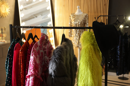 Racks with beautiful festive clothes, mannequin and mirror in dressing room, closeup