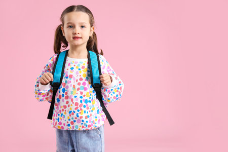 Cute schoolgirl with backpack on pink background. Space for text