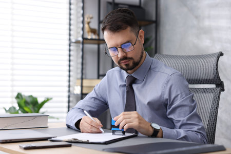 Notary stamping document at desk in office