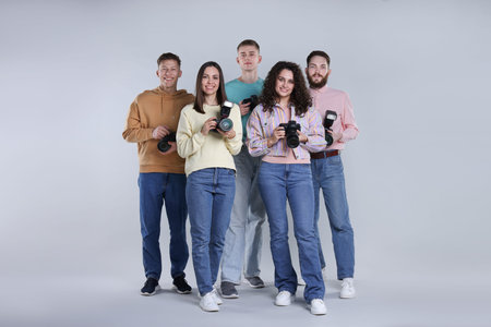 Group of photographers with professional cameras against light grey background