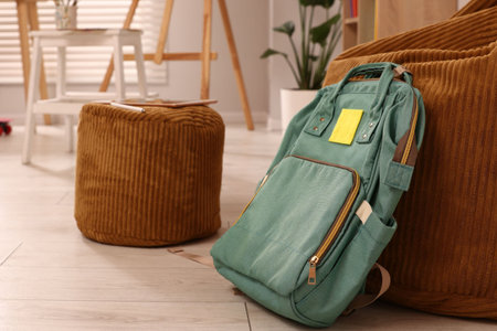 Teenager's room with stylish furniture, different art supplies and easel, focus on backpack....