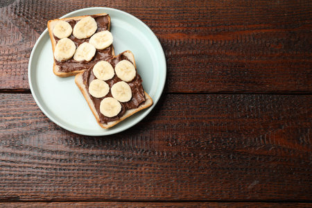 Toasts with chocolate paste and banana on wooden table, top view. Space for textの写真素材