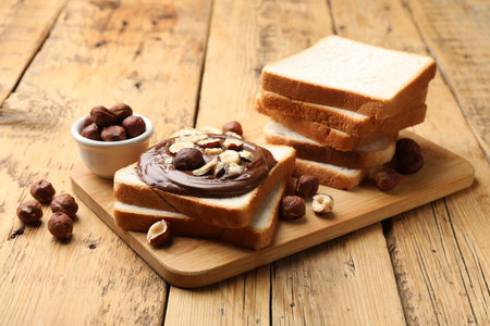 Toasts with chocolate paste and hazelnuts on wooden table, closeupの写真素材