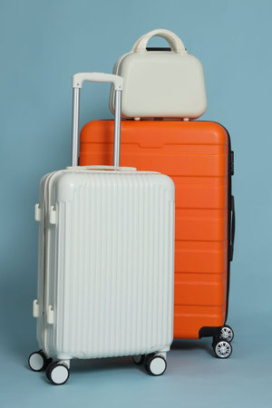 Three different stylish suitcases on light blue backgroundの写真素材