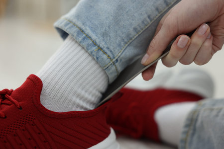 Woman putting on stylish sneakers with shoehorn at home, closeupの写真素材