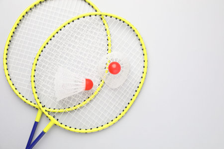 Badminton rackets and shuttlecocks on white background, top view. Space for text