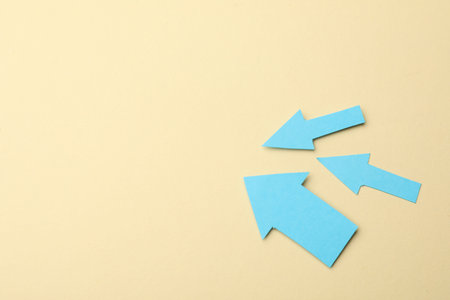 Light blue paper arrows on beige background, above view. Space for textの写真素材