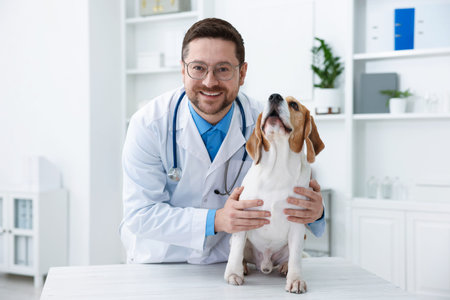 Smiling veterinarian in medical coat and glasses with stethoscope and cute dog at table in clinic