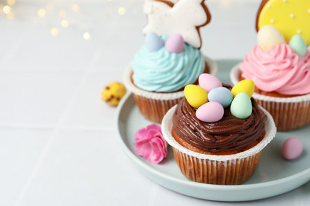 Tasty cupcakes with Easter decor on white table, closeup. Space for text