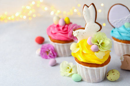 Tasty cupcakes with Easter decor on light grey table, closeup. Space for text