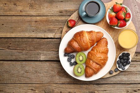 Healthy breakfast. Tasty croissants, kiwi, berries, orange juice and coffee on wooden table, top view. Space for textの写真素材