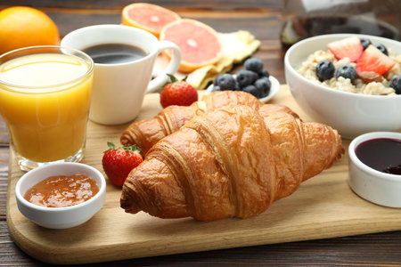 Healthy breakfast. Tasty croissants, jams, oatmeal with berries, orange juice and coffee on wooden...