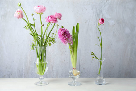 Beautiful pink flowers in glass vases on white table