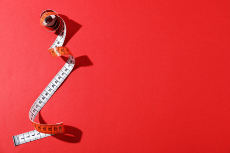 One measuring tape on red background, top view. Space for text
