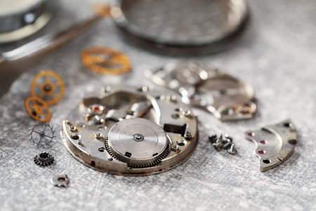 Mechanism of vintage wrist watch and gears on grey table, closeup