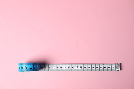 One measuring tape on pink background, top view. Space for text