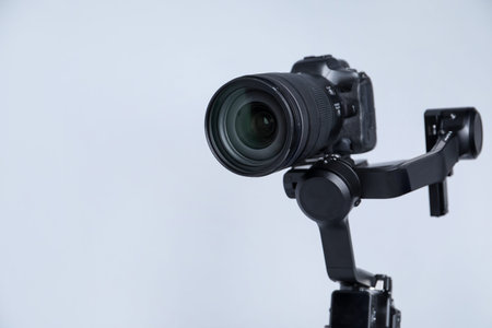 Gimbal stabilizer with camera on light background, closeup. Space for text