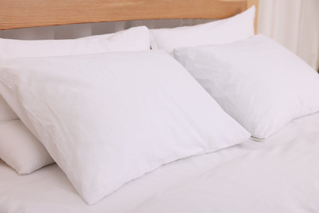 Comfortable bed with fresh cotton linens indoors, closeup