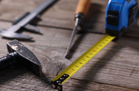 Measuring tape and other tools on wooden table, closeup