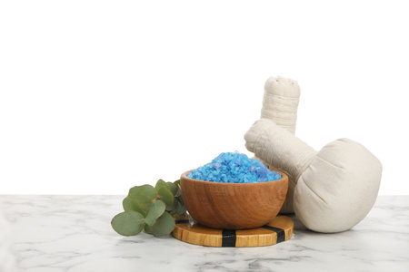 Blue sea salt in bowl, herbal bags and eucalyptus branch on marble table against white backgroundの写真素材
