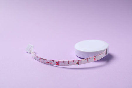 One measuring tape on violet background, closeup
