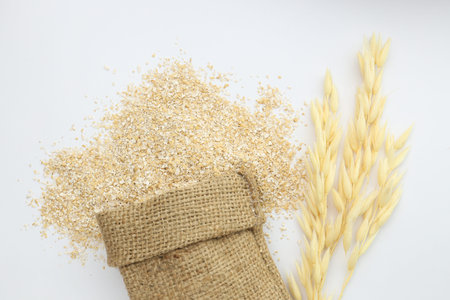 Oat bran in sack and spikes isolated on white, top view