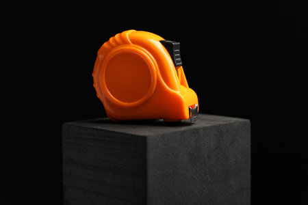 Measuring tape on block against black background, closeup