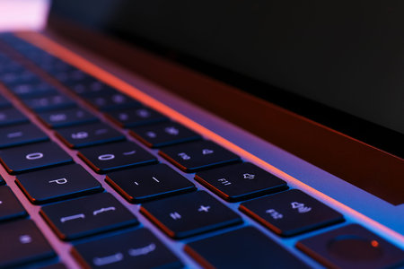 Stylish modern laptop in neon lights, closeup