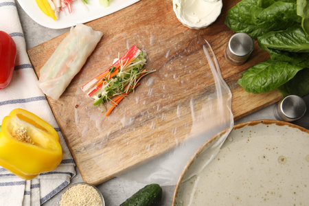 Making spring rolls. Rice paper with ingredients on grey table, flat lay