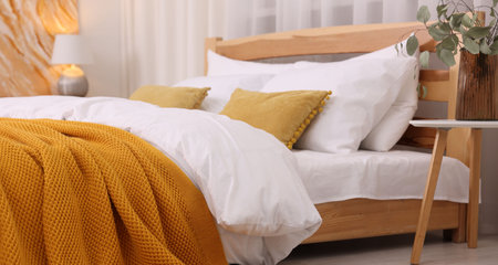 Comfortable bed with fresh cotton linens and plaid indoors, closeup