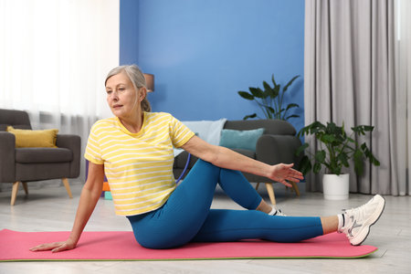 Senior woman exercising on mat at home, space for text. Fitness and sport