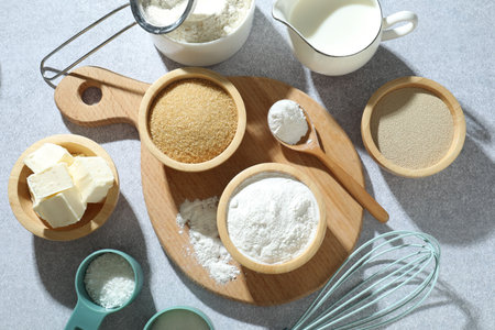 Baking powder and other ingredients for making dough on grey table, flat lay