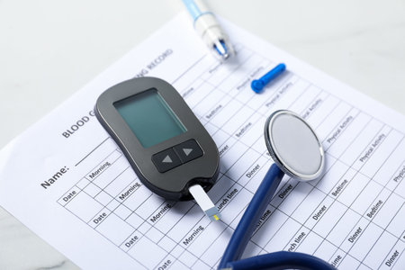 Diabetes. Digital glucometer with test strip, pen, lancet, stethoscope and record form on light...