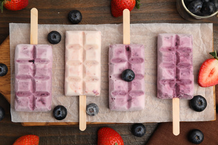 Tasty frozen yogurt and berries on wooden table, flat lay